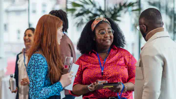 Three office workers talk at a mixer